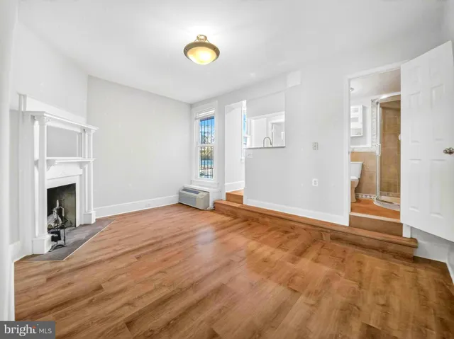 a view of empty room with fireplace and wooden floor