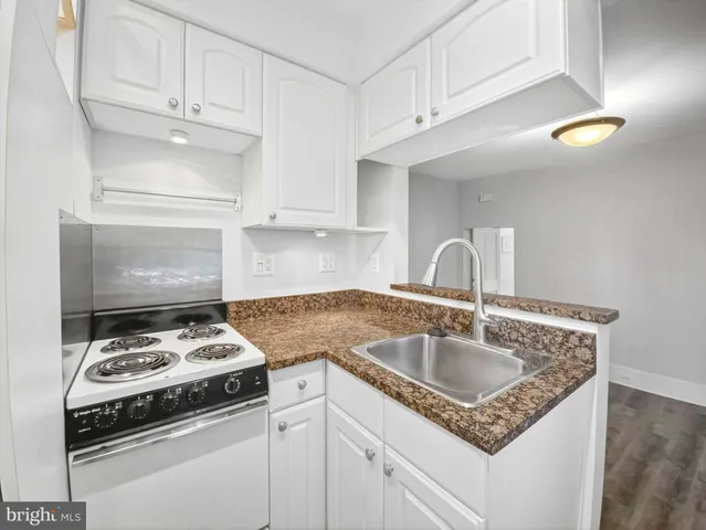 a kitchen with granite countertop a sink stove and cabinets