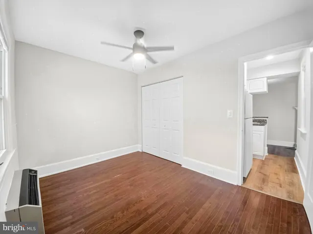 an empty room with wooden floor fan and windows