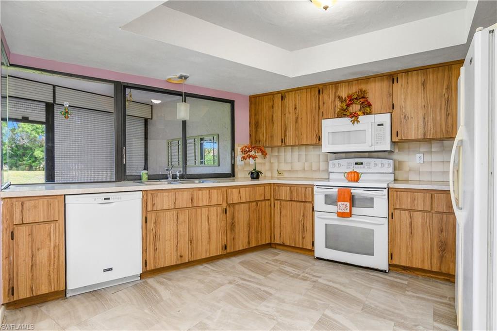 191 Round Key Circle, Unit D2 Naples, FL 34112 - Photo 12 of 24 a kitchen with granite countertop a refrigerator a sink and white cabinets