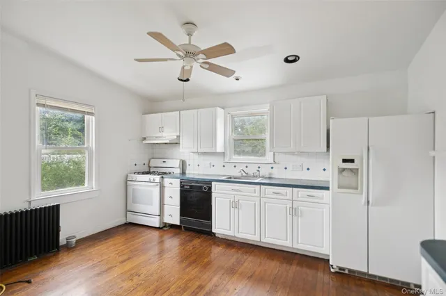 a kitchen with stainless steel appliances a sink a stove a refrigerator cabinets and a window