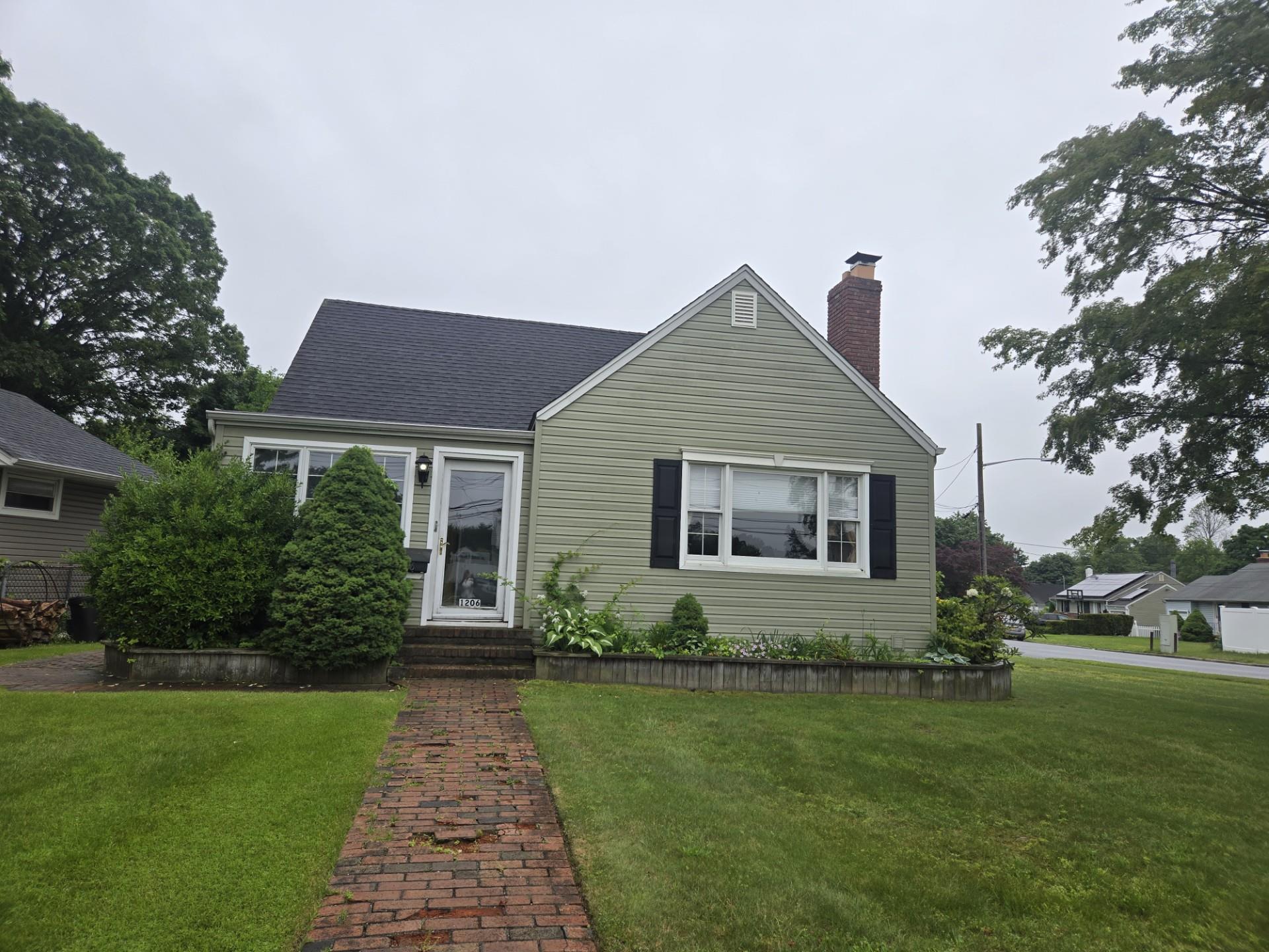 View of front of home with a front yard, a chimney, and entry steps