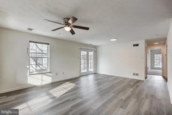 an empty room with wooden floor and windows