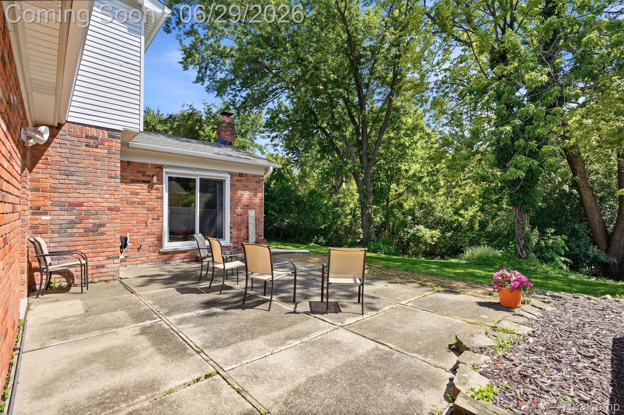 45179 Rudgate Road Canton, MI 48188 - Photo 28 of 48 Expansive concrete patio with direct access to interior spaces via a sliding glass door, featuring a brick exterior and mature trees providing natural screening
