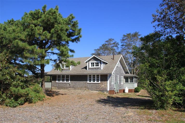 a front view of a house with a garden and trees