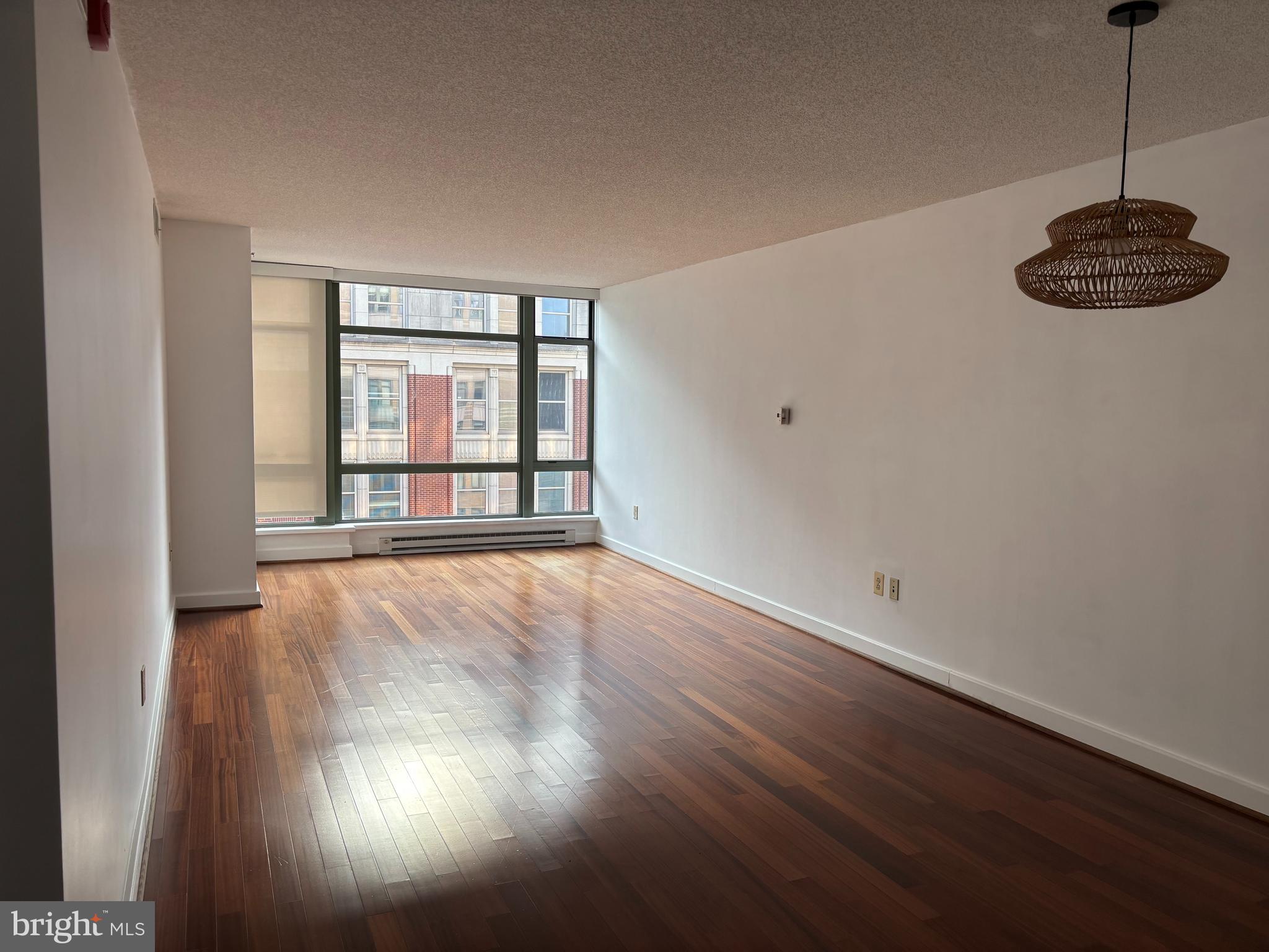 1150 K Street Northwest, Unit 1107 Washington, DC 20005 - Photo 5 of 20 a view of an empty room with window and wooden floor
