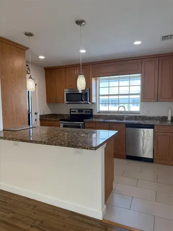 a kitchen with stainless steel appliances granite countertop a sink a stove a refrigerator and a microwave