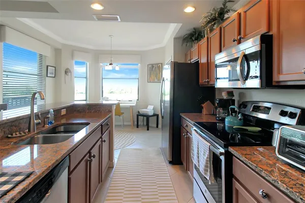 a kitchen with stainless steel appliances granite countertop a refrigerator a stove top oven a sink and dishwasher