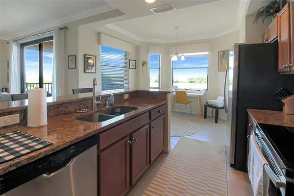 a kitchen with stainless steel appliances granite countertop a refrigerator a stove a sink a dining table and chairs with wooden floor