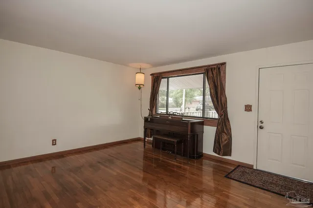 a view of an empty room with wooden floor and a fireplace
