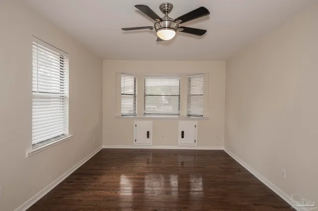 a view of empty room with wooden floor and fan