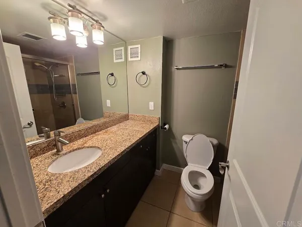 a bathroom with a granite countertop sink toilet and shower
