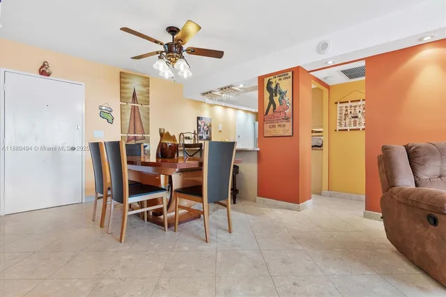 a dining room with furniture and a chandelier fan