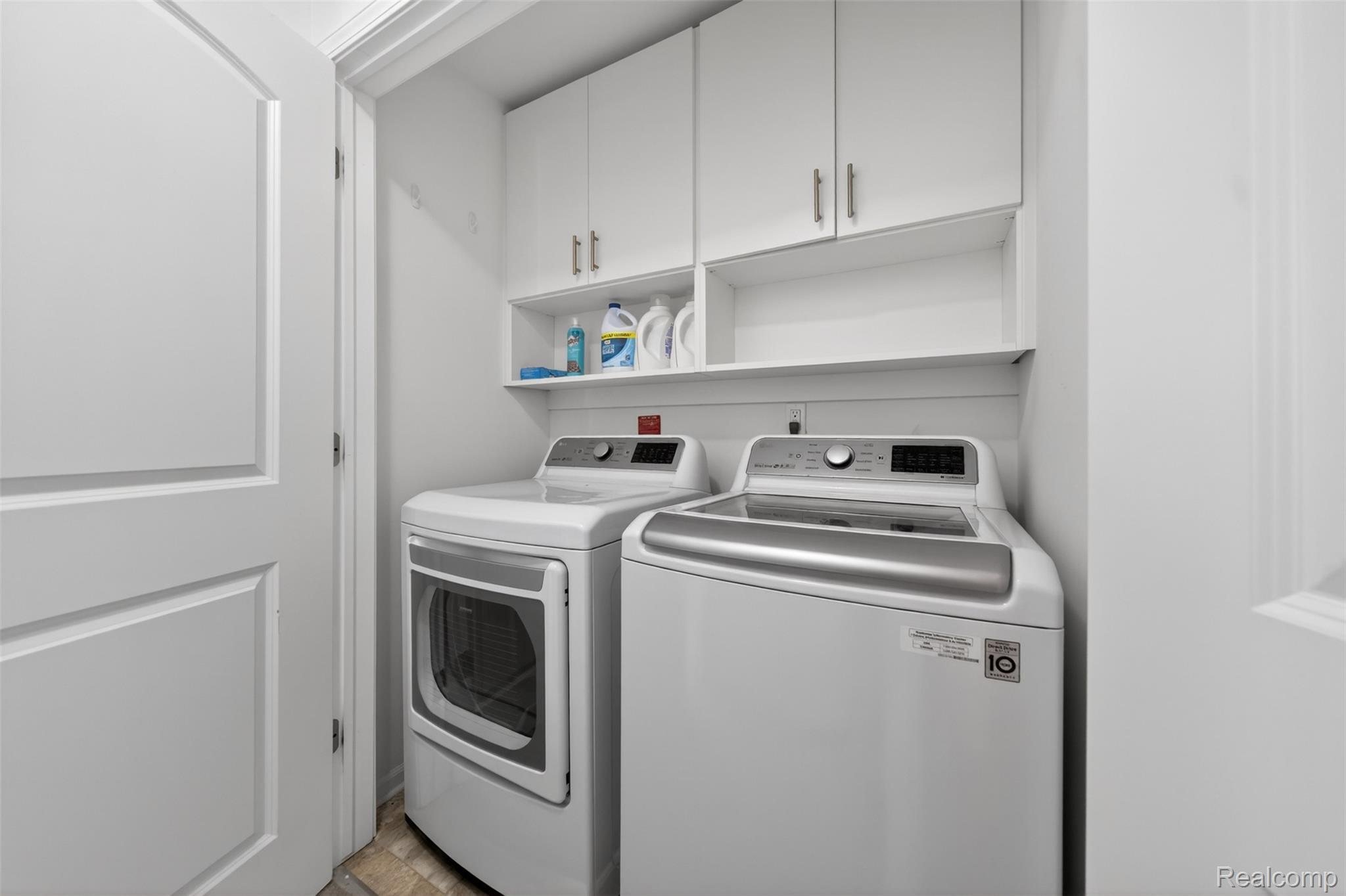 3534 South Rochester Road Royal Oak, MI 48073 - Photo 19 of 25 Dedicated laundry area featuring white cabinetry with silver hardware, open shelving, and a tiled floor