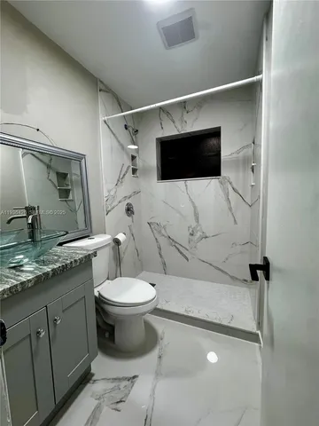 a bathroom with a granite countertop sink toilet and a mirror