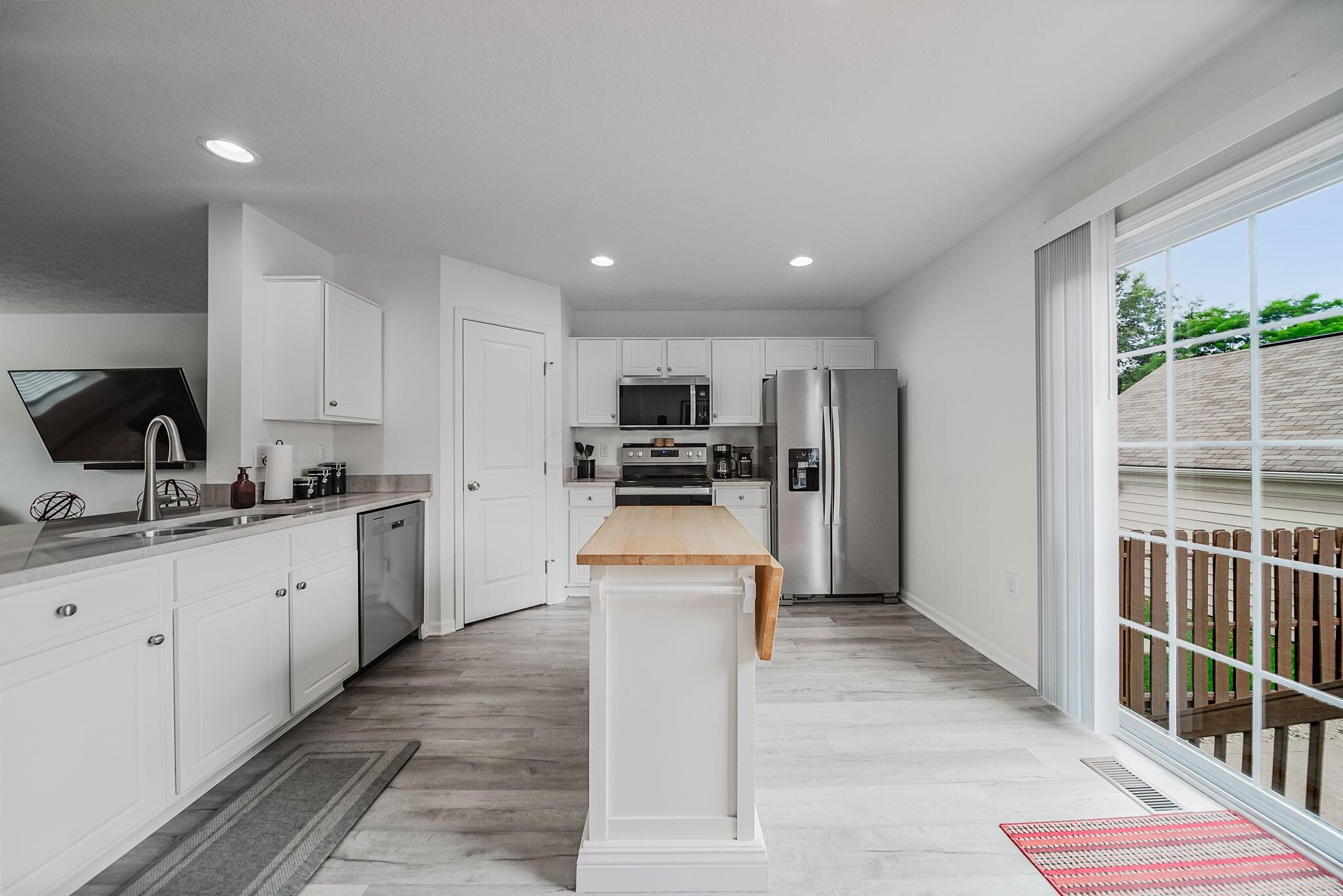 6186 Needletail Road, Unit 66 Columbus, OH 43230 - Photo 8 of 48 Beautiful white cabinetry with brand new (2026) honed granite counters, LVP flooring, and rececced lighting. Large sliding door leads to backyard and garage and floods the area with natrual light!