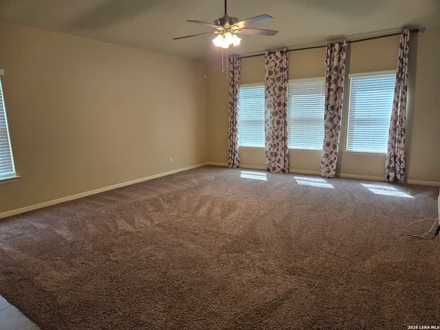 a view of an empty room with chandelier fan and a fireplace