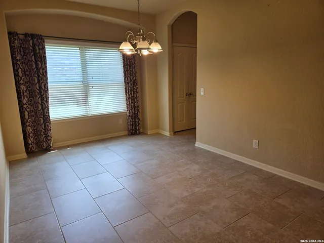 an empty room with chandelier fan and windows