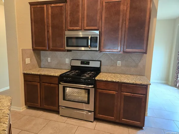 a kitchen with granite countertop wood cabinets and stainless steel appliances