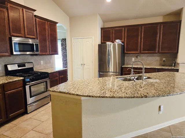 a kitchen with kitchen island granite countertop a stove refrigerator and microwave