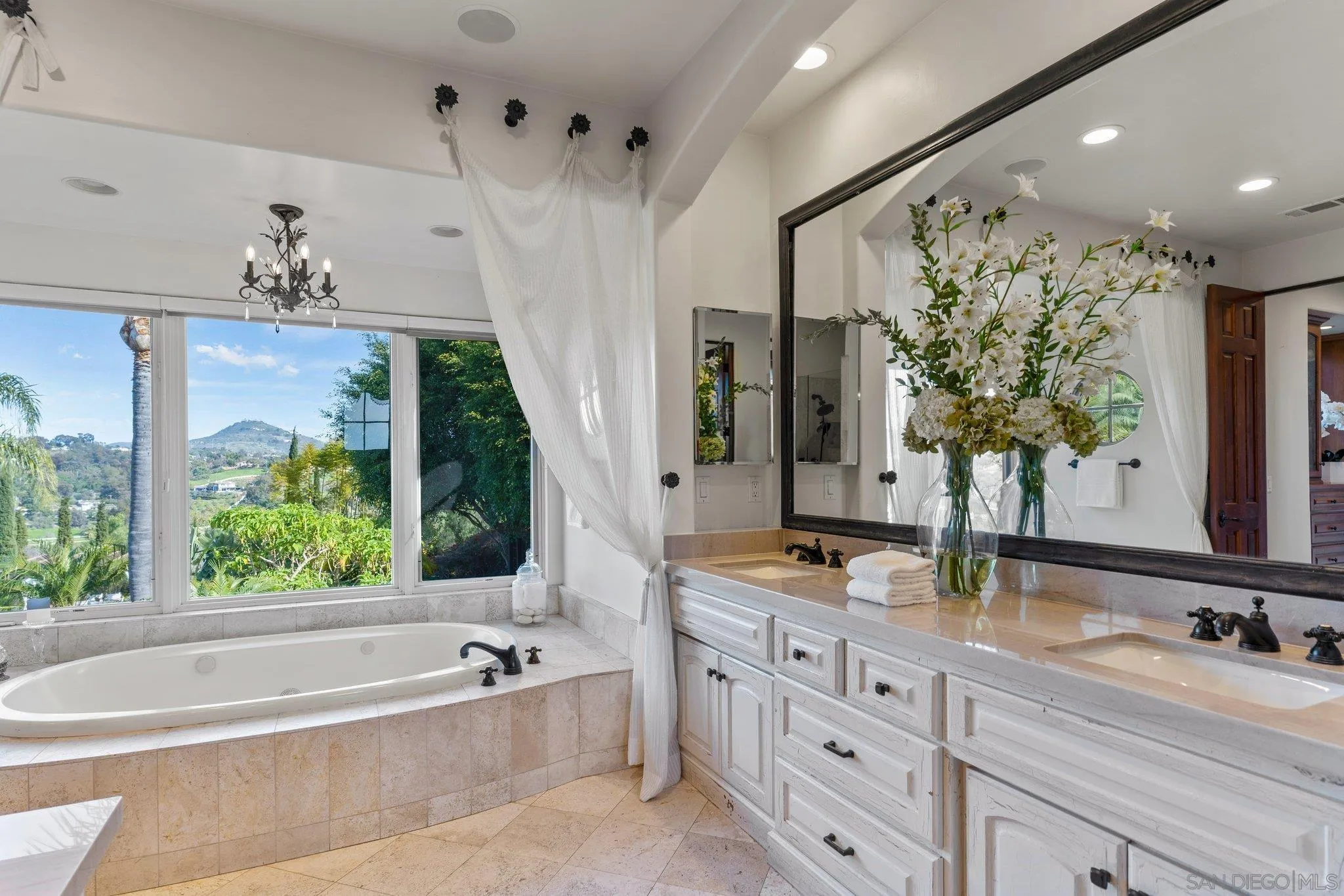 3381 Calle Margarita Encinitas, CA 92024 - Photo 17 of 47 a bathroom with double vanity sinks a large mirror and a bathtub next to a window