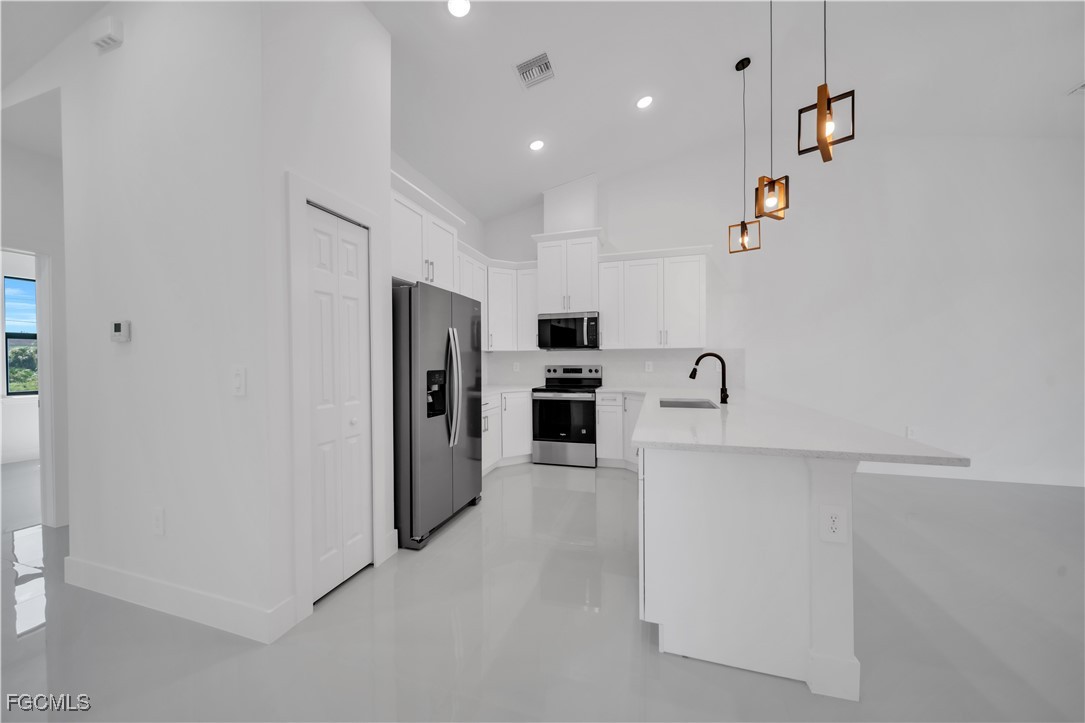 1110 Eisenhower Boulevard Lehigh Acres, FL 33974 - Photo 11 of 35 a view of a kitchen with refrigerator and white cabinets