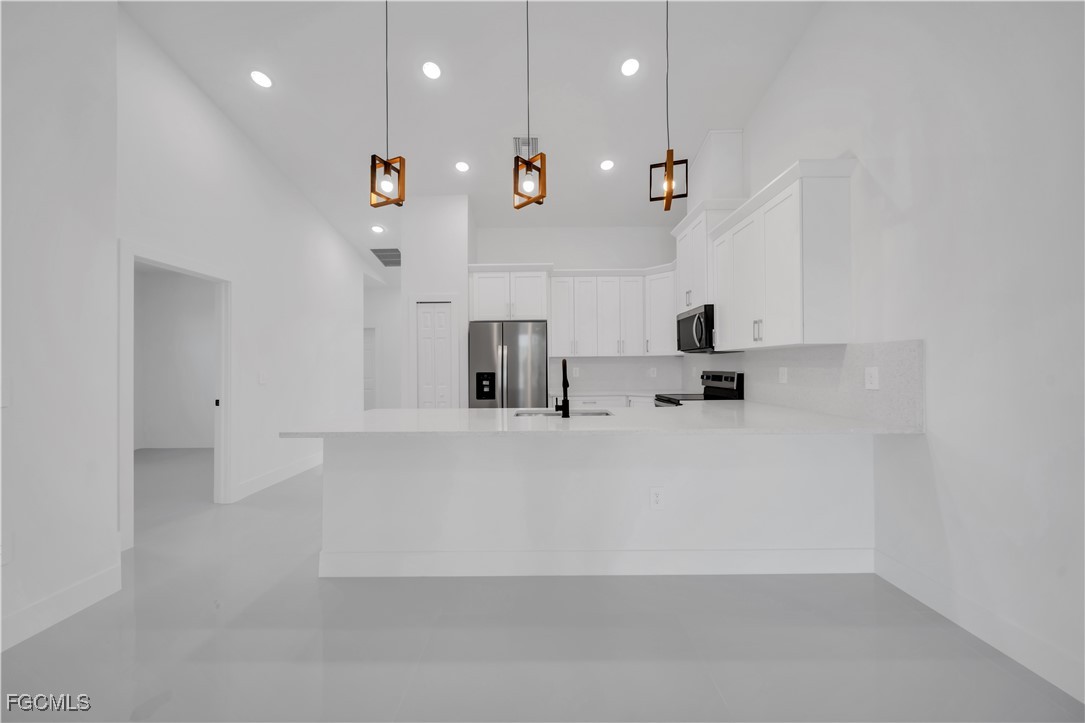 1110 Eisenhower Boulevard Lehigh Acres, FL 33974 - Photo 17 of 35 a view of kitchen with kitchen island stainless steel appliances a sink a refrigerator and a stove