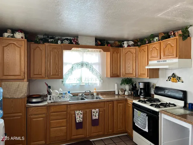 a kitchen with granite countertop a stove a sink dishwasher and cabinets with wooden floor