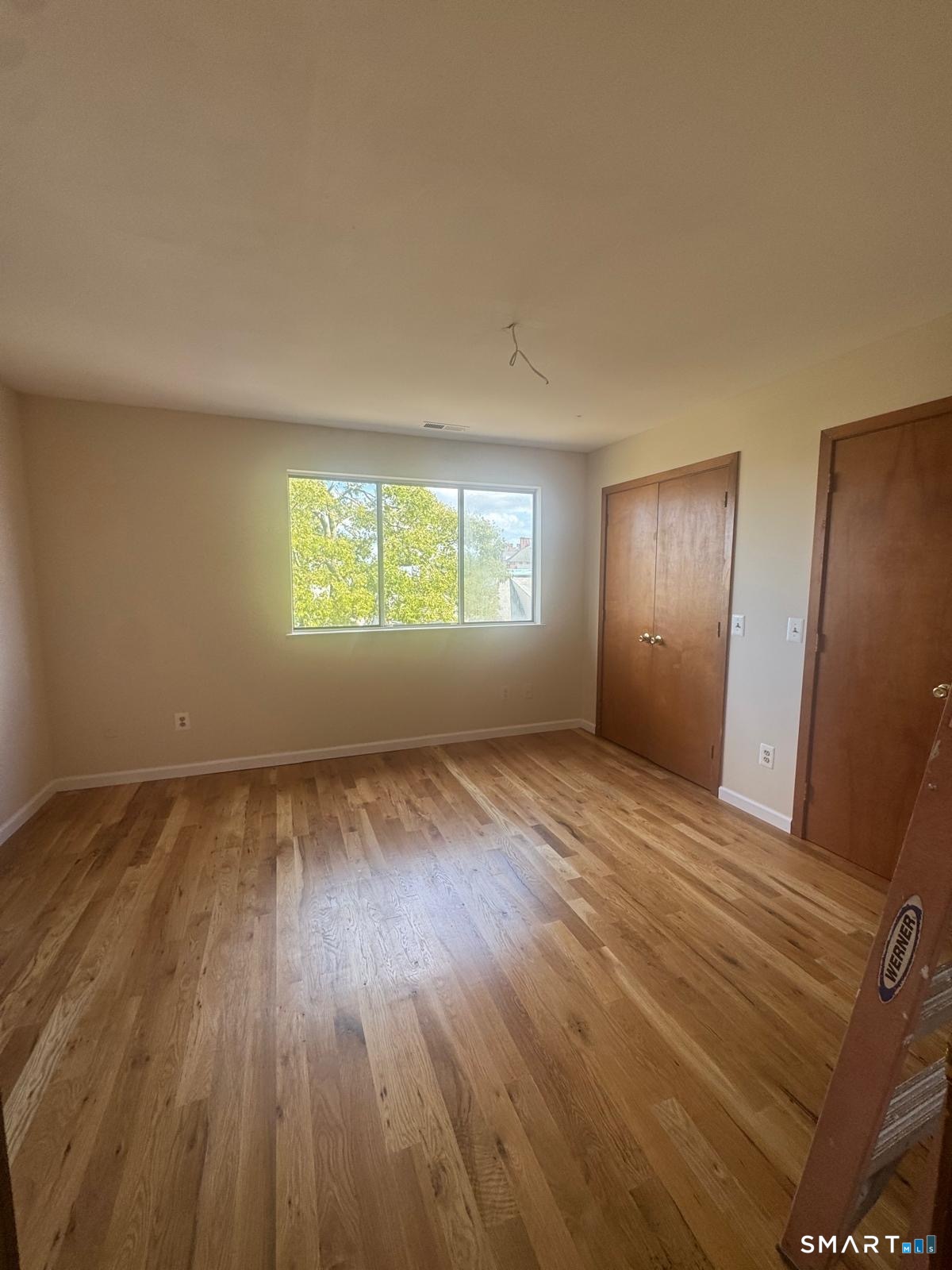 204 Wheeler Avenue, Unit 9 Bridgeport, CT 06606 - Photo 3 of 11 a view of an empty room with wooden floor and window