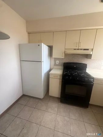 a white kitchen with a stove a refrigerator and a sink