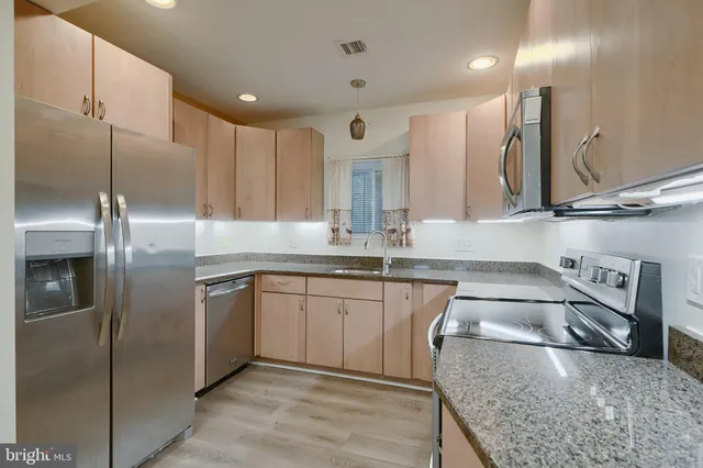 a kitchen with stainless steel appliances granite countertop a sink a stove and a refrigerator