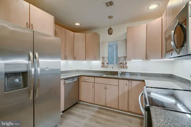 a kitchen with stainless steel appliances granite countertop a refrigerator a sink a stove with white cabinets