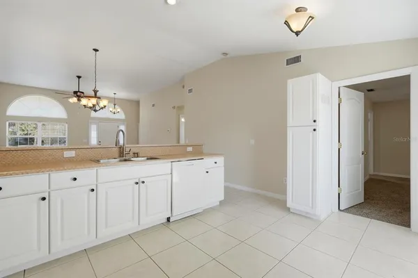 a kitchen with granite countertop white cabinets white appliances and a sink