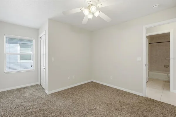 an empty room with a window and a ceiling fan