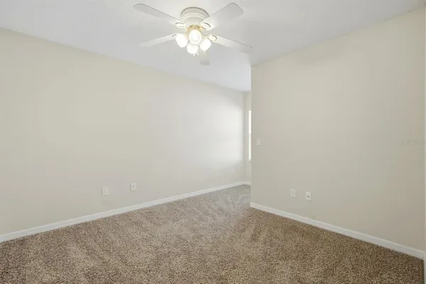 an empty room with a window and a ceiling fan
