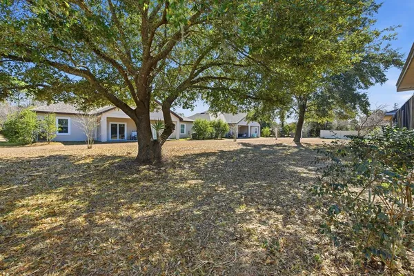 a view of a house with a yard and large tree