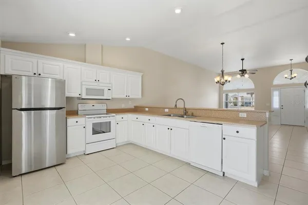 a kitchen with white cabinets stainless steel appliances and a chandelier