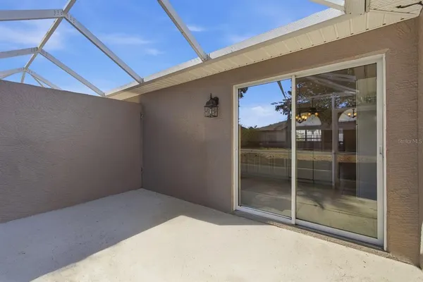 an empty room with kitchen view and a chandelier fan
