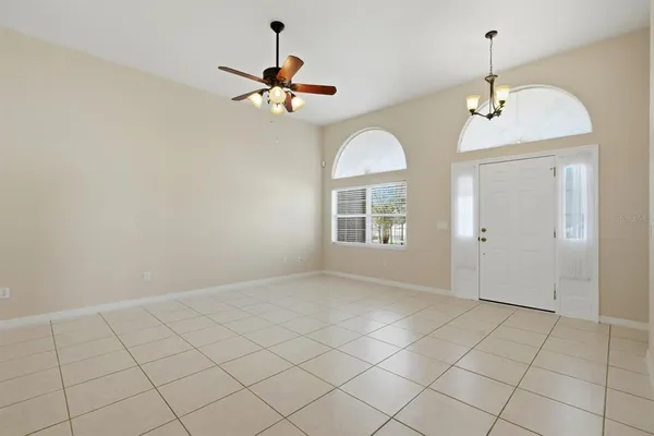 an empty room with chandelier fan and glass door