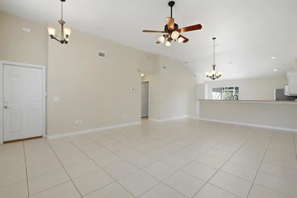 an empty room with chandelier fan and glass door