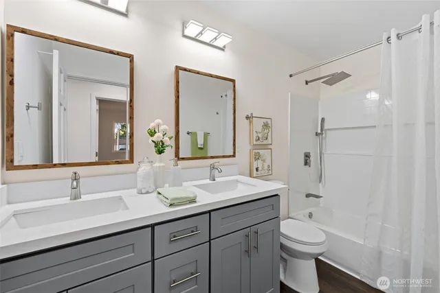 a bathroom with a double vanity sink toilet mirror and shower