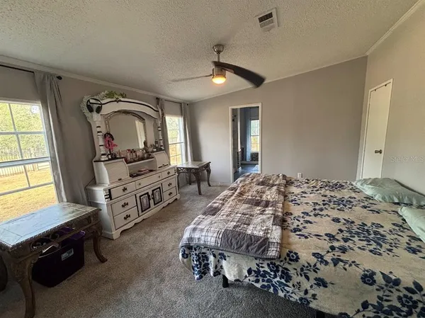 a spacious bedroom with a bed a dresser and large mirror