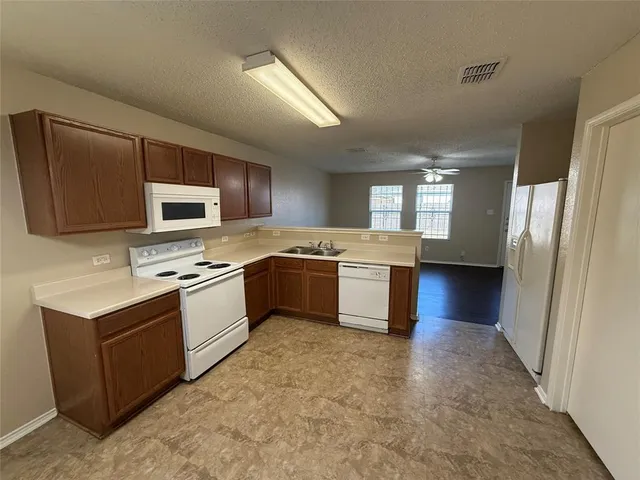 a kitchen with stainless steel appliances a stove a sink a microwave a refrigerator a window and white cabinets