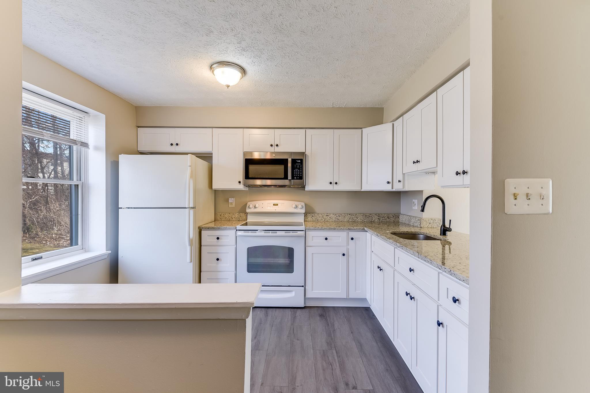 7946 Sutherland Court Pasadena, MD 21122 - Photo 9 of 37 a kitchen with stainless steel appliances granite countertop a refrigerator sink and white cabinets