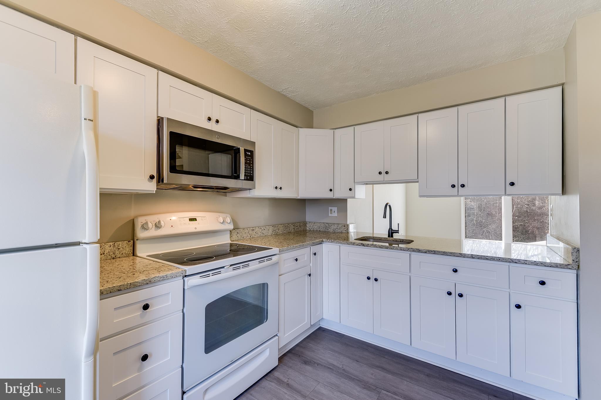 7946 Sutherland Court Pasadena, MD 21122 - Photo 10 of 37 a kitchen with cabinets stainless steel appliances and a wooden floor