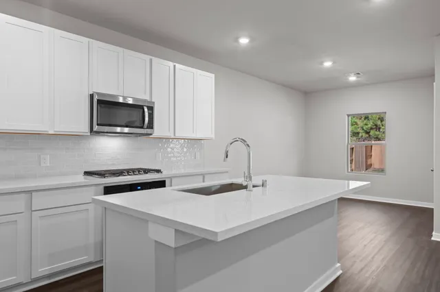 a kitchen with a sink a microwave and cabinets