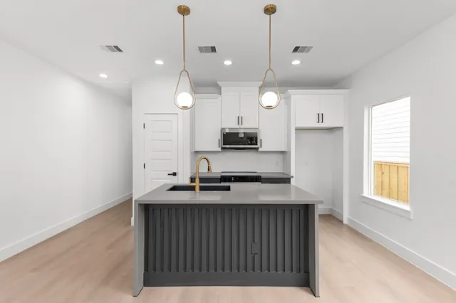 a kitchen with kitchen island granite countertop a sink a counter space appliances and a window