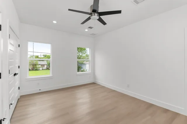 an empty room with windows and a ceiling fan
