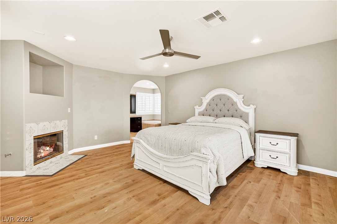 1135 Calico Ridge Drive Henderson, NV 89011 - Photo 30 of 86 A comforting bedroom features a fireplace and a spacious layout with rich wood-look flooring.