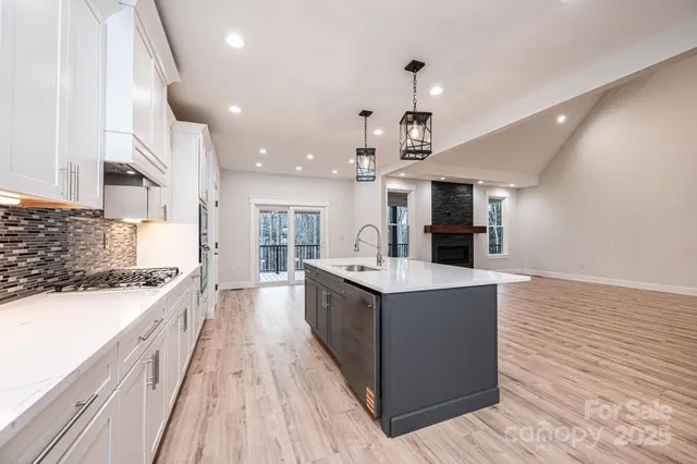 a large kitchen with stainless steel appliances a large counter top a stove and a wooden floors